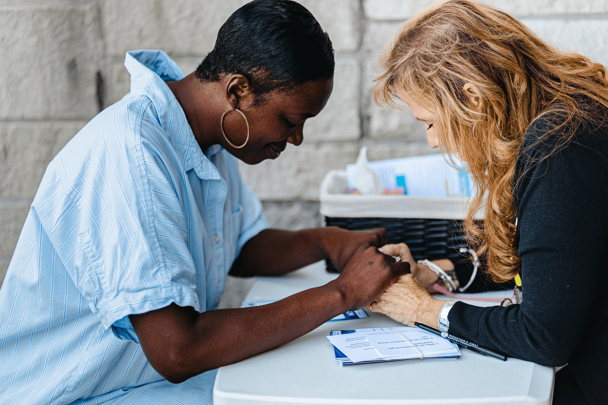 Women praying together at a table at HFBC